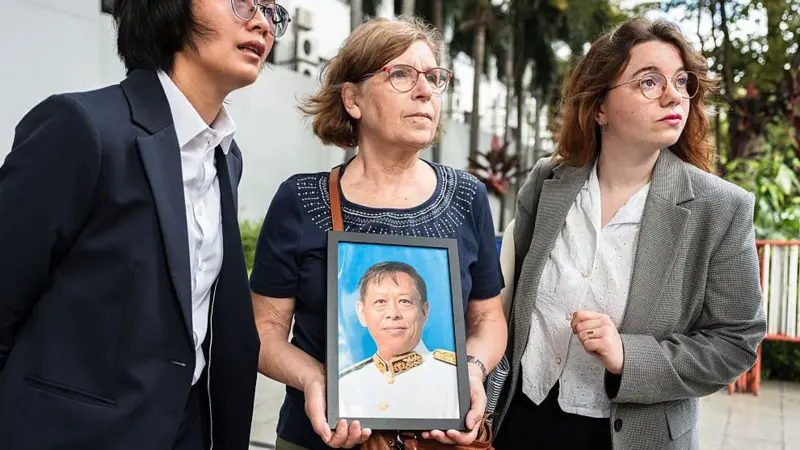 ครอบครัวผู้เสียหายถือภาพนายลิม กิมยา